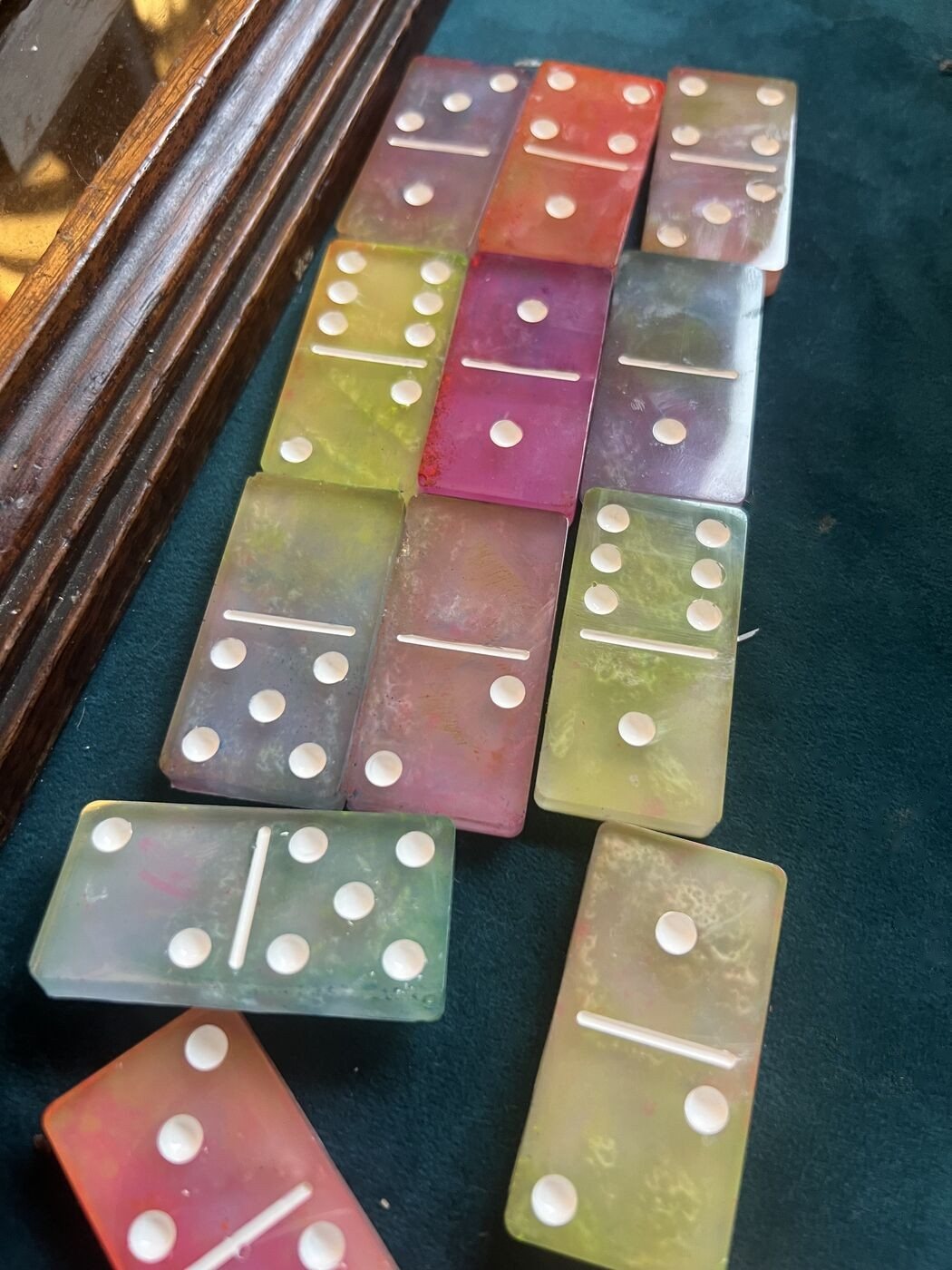 Rows of rainbow resin dominoes on green felt