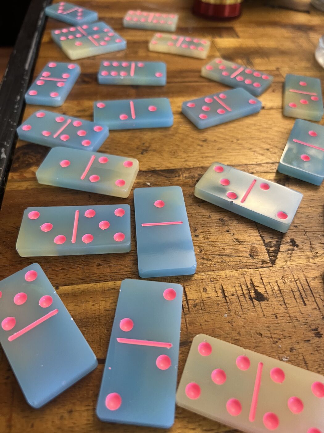 Sky blue and butter yellow resin dominoes with neon pink pips on a wood table